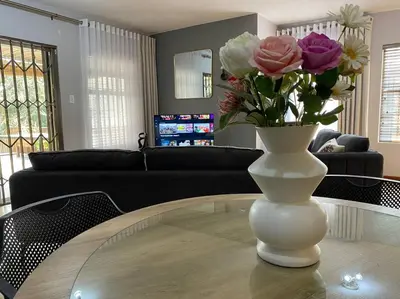 a white vase with flowers on a table in a living room at LA Montranquilo-Home of comfort in Pretoria