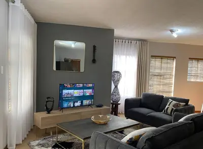 a living room with a couch and a tv at LA Montranquilo-Home of comfort in Pretoria