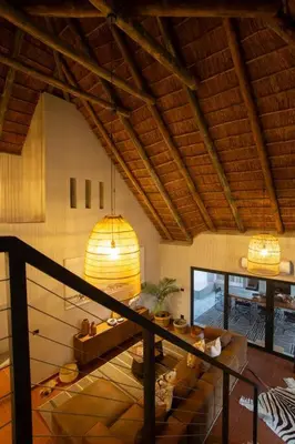 a living room with a staircase in a house at Bateleur Kruger Lodge in Marloth Park