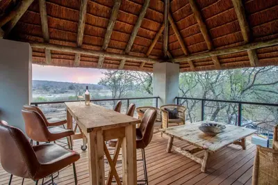 a dining room with a table and chairs on a deck at Bateleur Kruger Lodge in Marloth Park
