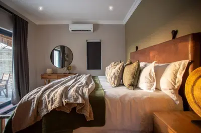 a bedroom with a bed with pillows and a mirror at Bateleur Kruger Lodge in Marloth Park