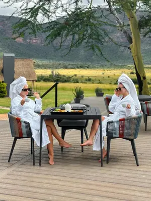 two women in white robes sitting at a table at Honeyguide Conservation Lodge in Golders Green