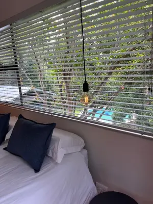 a bedroom with a window with blinds and a bed at Apartments on Herbert Baker in Pretoria