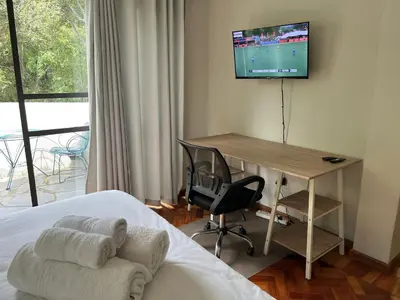 a bedroom with a desk and a television on a wall at Apartments on Herbert Baker in Pretoria