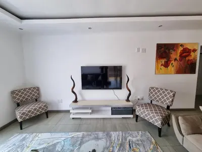 a living room with a couch and a tv at Kanyamazane Guesthouse 1214 in eNyamazaneni