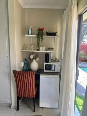 a kitchen with a table with a microwave and a chair at 17 Byvanger Luxury Home Deluxe King Suite Room 3 in Centurion
