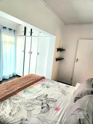 a bedroom with a bed and white cabinets at Escape in Pretoria