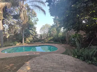 a swimming pool in a garden with a brick walkway around it at Escape in Pretoria