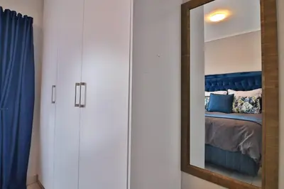 a mirror in a room with a bed and a blue curtain at Lowveld Vivid Haven in Boschrand