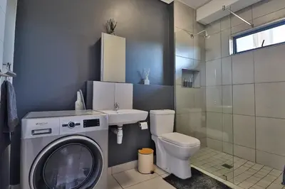 a bathroom with a washing machine and a toilet at Lowveld Vivid Haven in Boschrand