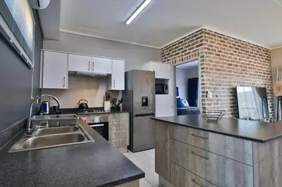 a kitchen with stainless steel appliances and a brick wall at Lowveld Vivid Haven in Boschrand