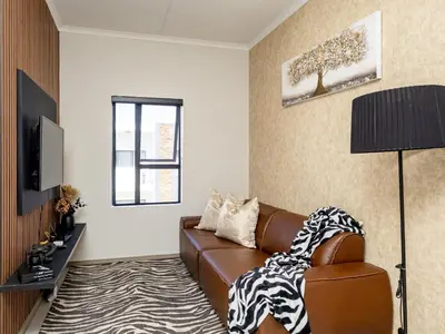 a living room with a brown leather couch and a television at Anna Suite - Serenity & Stuff Luxury Apartments in Midrand