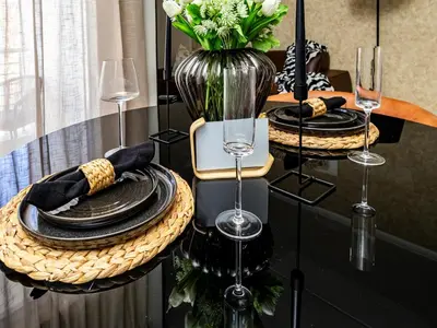 a table with black plates and a vase with flowers at Anna Suite - Serenity & Stuff Luxury Apartments in Midrand