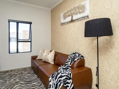a living room with a brown leather couch and a lamp at Anna Suite - Serenity & Stuff Luxury Apartments in Midrand