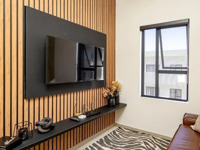 a living room with a television on a wall at Anna Suite - Serenity & Stuff Luxury Apartments in Midrand