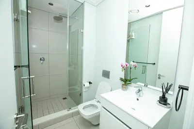 a bathroom with a shower and a toilet and a sink at Ellipse Executive Haven in Midrand