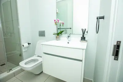 a white bathroom with a toilet and a sink at Ellipse Executive Haven in Midrand