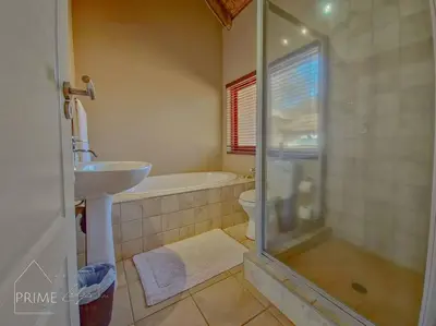 a bathroom with a shower and a sink and a toilet at Rhino Lodge at Zebula in Mabula