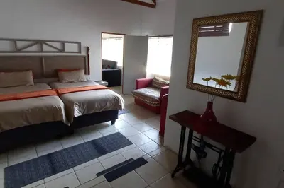 a bedroom with a bed and a mirror and a chair at Bergsig Self-Catering Accommodation - Sabie in Sabie