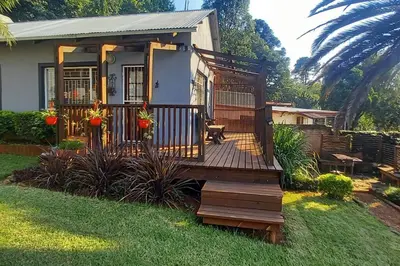 a tiny house with a wooden deck in a yard at Bergsig Self-Catering Accommodation - Sabie in Sabie