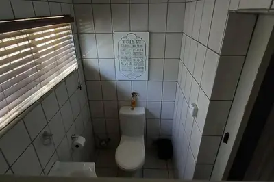 a bathroom with a toilet and a sign on the wall at Bergsig Self-Catering Accommodation - Sabie in Sabie