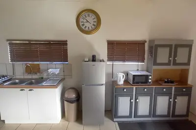 a kitchen with a refrigerator and a clock on the wall at Bergsig Self-Catering Accommodation - Sabie in Sabie