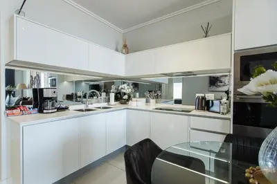 a kitchen with white cabinets and a glass table at Apartment Ellipse Waterfall in Midrand
