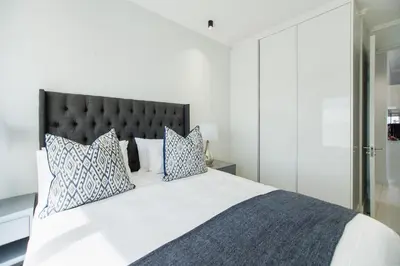 a bedroom with a large white bed with blue pillows at Apartment Ellipse Waterfall in Midrand