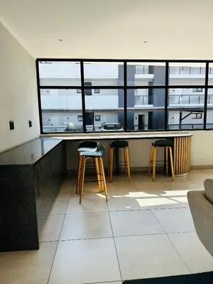 a kitchen with two stools and a counter with windows at Luxury Studio Apartment next to Brooklyn Mall in Pretoria