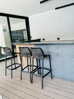 two chairs sitting next to a bar on a deck at Luxury Studio Apartment next to Brooklyn Mall in Pretoria