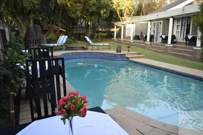 a swimming pool with a vase of flowers on a table at The Lion Room at Frederick's Place in Pretoria