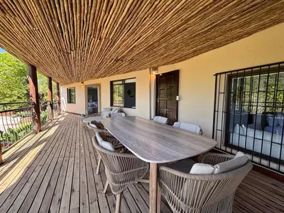 a wooden deck with a wooden table and chairs at Khenjadji at Fish Eagle Bay in Warmbaths