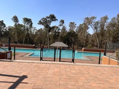 a swimming pool with a fence and an umbrella at Tetani's Luxury Oasis in Lakeside