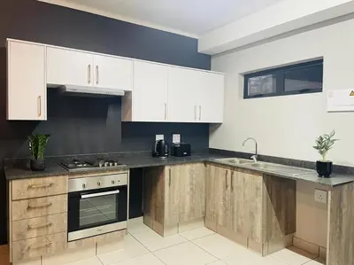 a kitchen with white cabinets and a sink at Apparent Self Catering in Boschrand