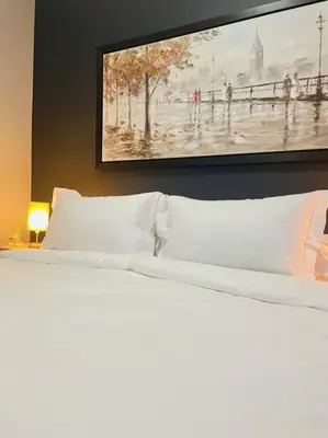 a bedroom with a white bed with a painting on the wall at Apparent Self Catering in Boschrand
