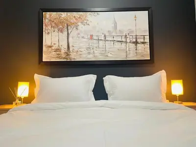 a bedroom with a white bed with a painting on the wall at Apparent Self Catering in Boschrand