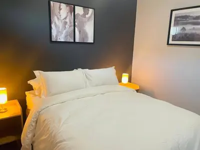 a bedroom with a white bed with three pictures on the wall at Apparent Self Catering in Boschrand