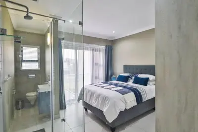 a bedroom with a bed and a bathroom with a shower at Hartbeespoort Dam Getaway Home in Kosmos