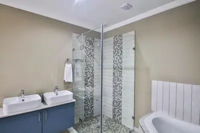 a bathroom with a shower and a sink and a tub at Hartbeespoort Dam Getaway Home in Kosmos