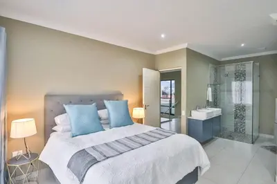 a bedroom with a bed and a bathroom with a shower at Hartbeespoort Dam Getaway Home in Kosmos