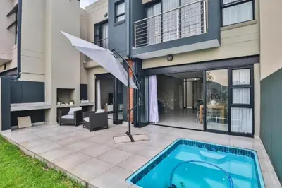 a house with an umbrella and a swimming pool at Hartbeespoort Dam Getaway Home in Kosmos