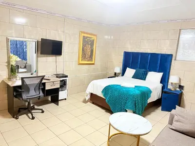 a bedroom with a bed and a desk and a computer at Whizzy lifestyle lodge in Duvhapark
