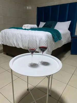 two glasses of red wine on a table next to a bed at Whizzy lifestyle lodge in Duvhapark