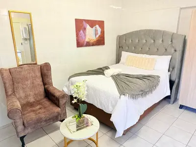 a bedroom with a bed and a chair at Whizzy lifestyle lodge in Duvhapark