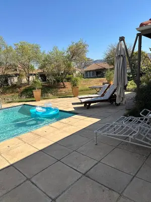 a swimming pool with an umbrella and a chair at Pecanwood Holiday Home in Kosmos