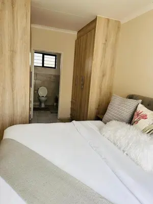 a bedroom with a large white bed and a bathroom at 02 in Bel Aire place in Kempton Park