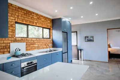 a kitchen with blue cabinets and a brick wall at Sink Huis at Benlize in Pelindaba