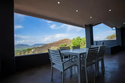 a dining room with a table and chairs and a large window at Sink Huis at Benlize in Pelindaba