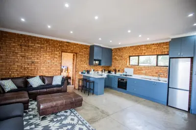 a living room with a couch and a kitchen at Sink Huis at Benlize in Pelindaba