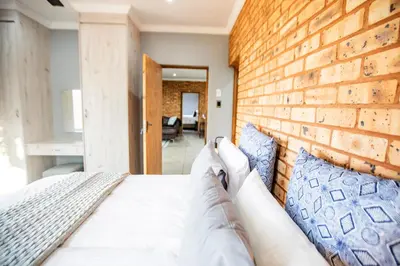 a bedroom with a brick wall and a bed at Sink Huis at Benlize in Pelindaba